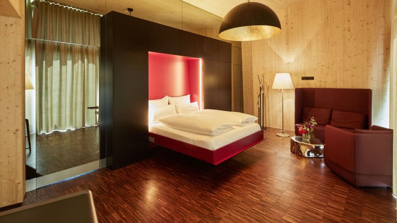 Interior view of a modern bedroom with floating bed, wood paneling and stylish lighting.