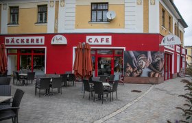 Exterior view of a bakery and café with seating area in Grimmenstein.