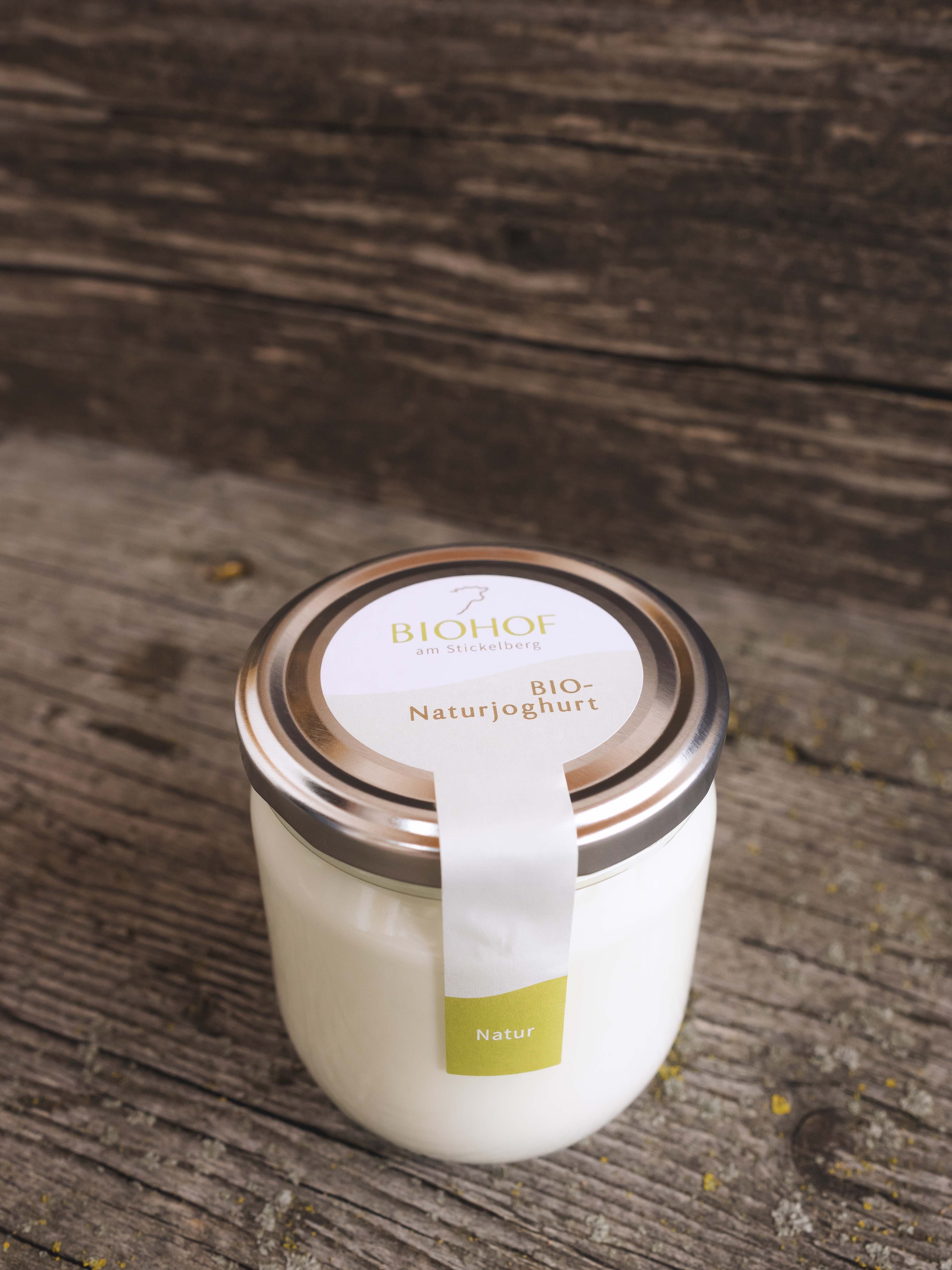 Ein Glas mit Bio-Naturjoghurt auf einem Holzboden.