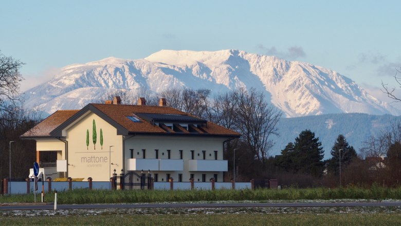 Außenansicht Schneebergblick, © Mattone GmbH Gebäude mit der Aufschrift 'mattone apartments' vor schneebedecktem Berg im Hintergrund.