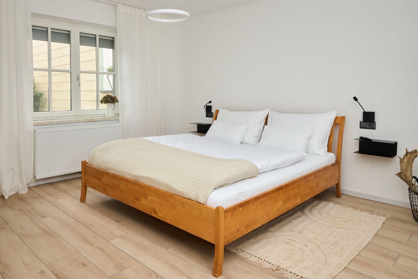 Bright bedroom with double bed, window, TV and chair.