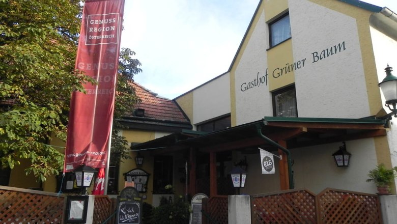 Eingang des Gasthofs Gr&uuml;ner Baum mit rotem Banner und Willkommensschild.