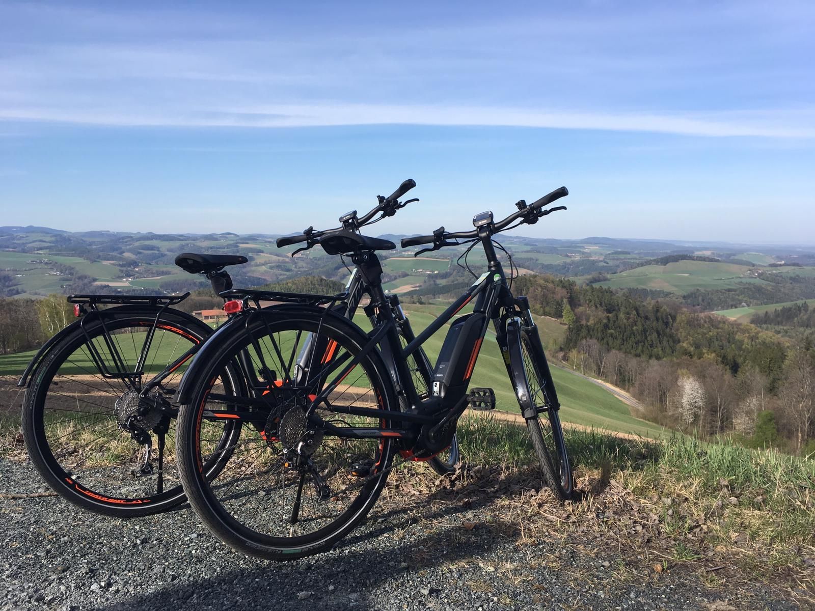 Zwei E-Bikes stehen auf einem Hügel mit Blick auf eine hügelige Landschaft.