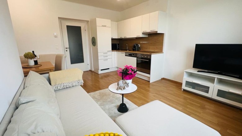 Moderne Wohnküche mit Sofa, Esstisch, Küchenzeile und Fernseher.