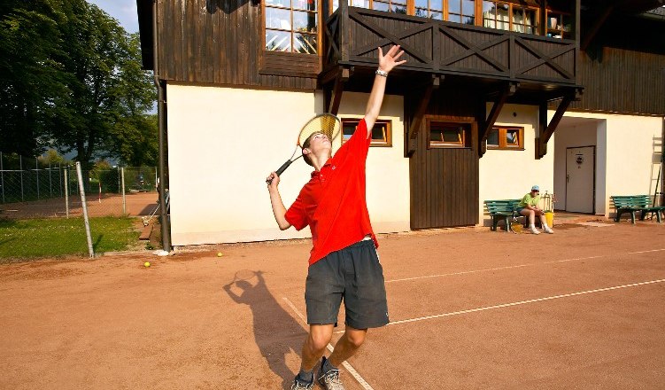Person beim Tennisspielen vor einem Gebäude.