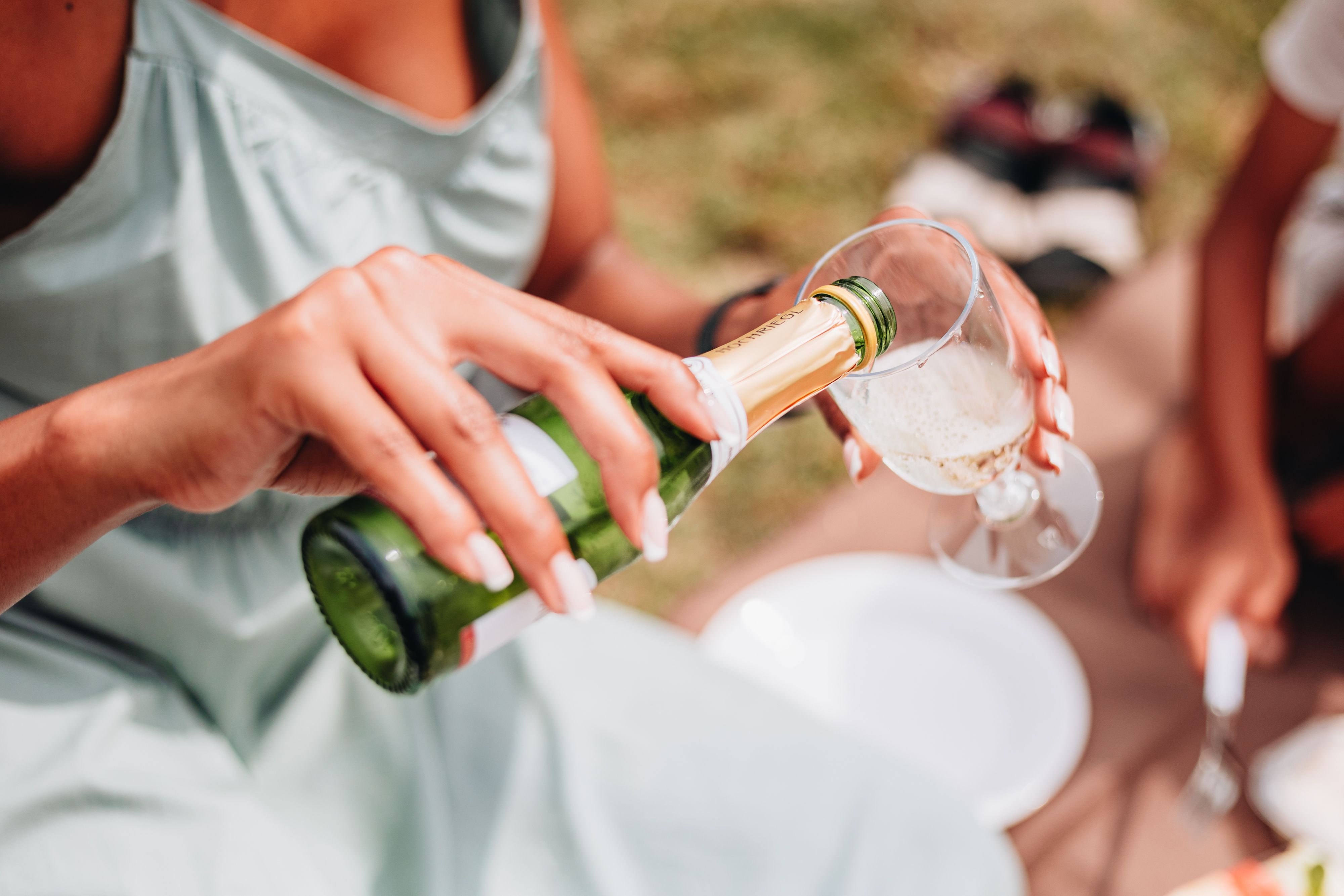 Eine Frau schenkt Sekt in ein Glas ein. 