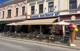 Außenansicht eines Eissalons mit Terrasse und Eistüten-Dekoration.