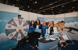 Eine Gruppe vor dem Glücksrad mit dem Wiener Alpen Schild