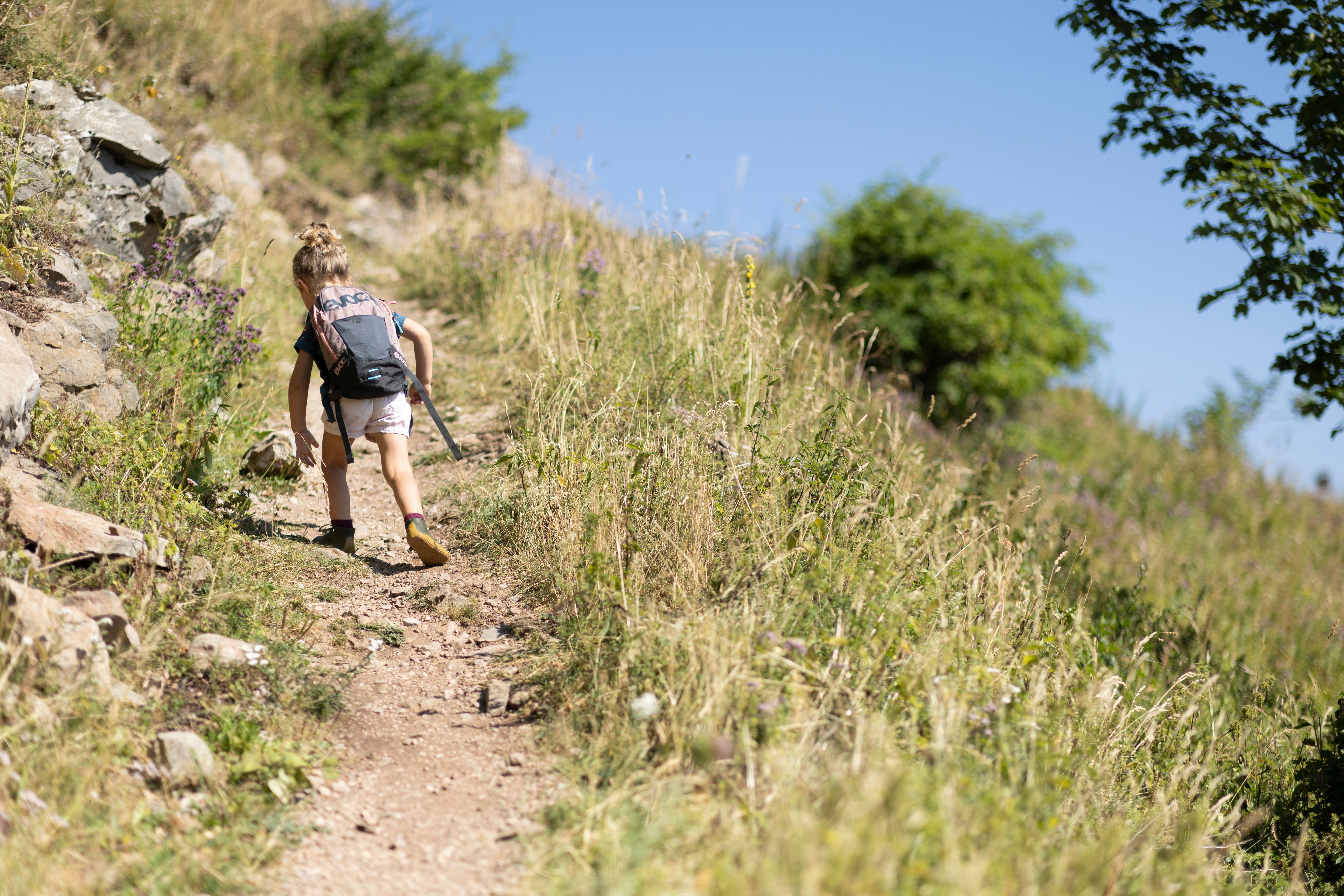 Kind wandert am Wanderweg mit Rucksack 