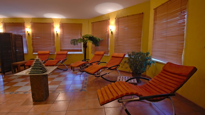 A wellness area with sun loungers, plants and subdued lighting.