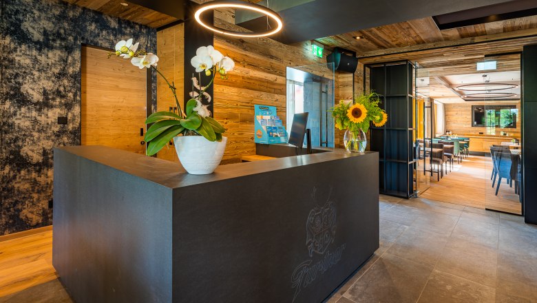 Moderne Rezeption mit Holzverkleidung, Orchideen und Sonnenblumen auf dem Tresen.