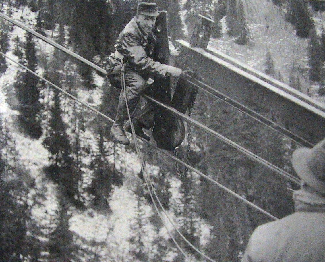 Historische Aufnahme in schwarz-weiß von einem Mann der gerade am Seil der Seilbahn arbeitet
