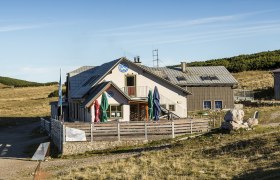 Das Damb&ouml;ckhaus am Schneeberg in einer sonnigen Berglandschaft mit blauem Himmel.