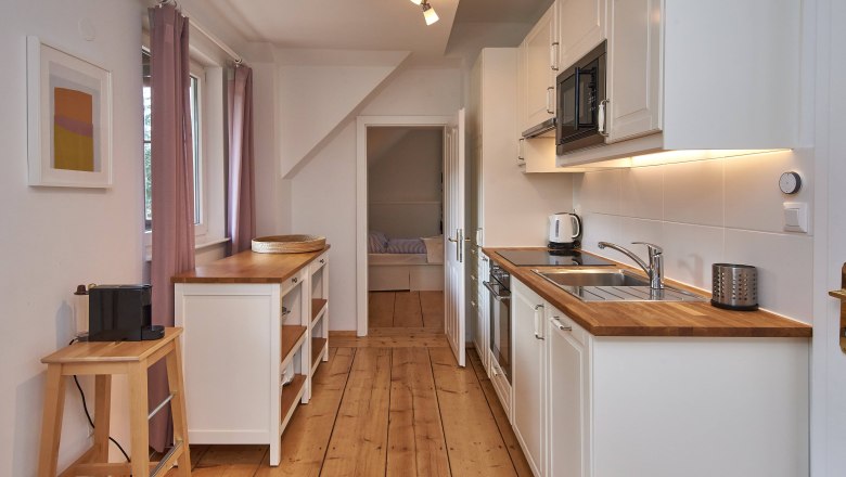 Moderne Küche mit Holzarbeitsplatten, weißen Schränken und Geräten.