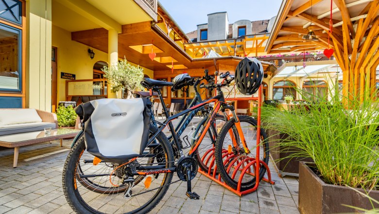 Bicycles on a bicycle stand in front of a hotel building.