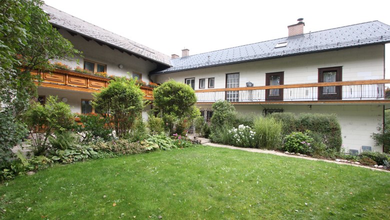 Ein traditionelles Haus mit Holzbalkon und gepflegtem Garten.