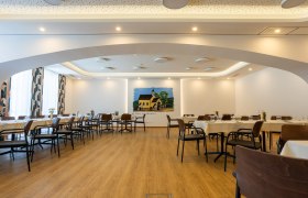 Innenansicht eines modernen Wirtshauses mit gedeckten Tischen und einem Wandgem&auml;lde.