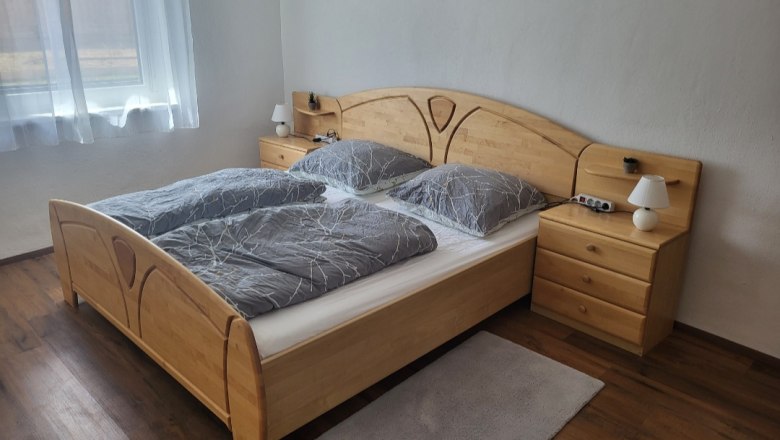 Bedroom with double bed, wooden furniture and gray bed linen.