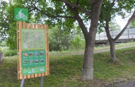 Radstartplatz-Tafel in Lanzenkirchen mit Karte und Informationen, umgeben von Bäumen.
