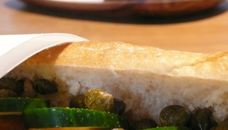 Close-up of a sandwich with cucumber, tomatoes and capers.