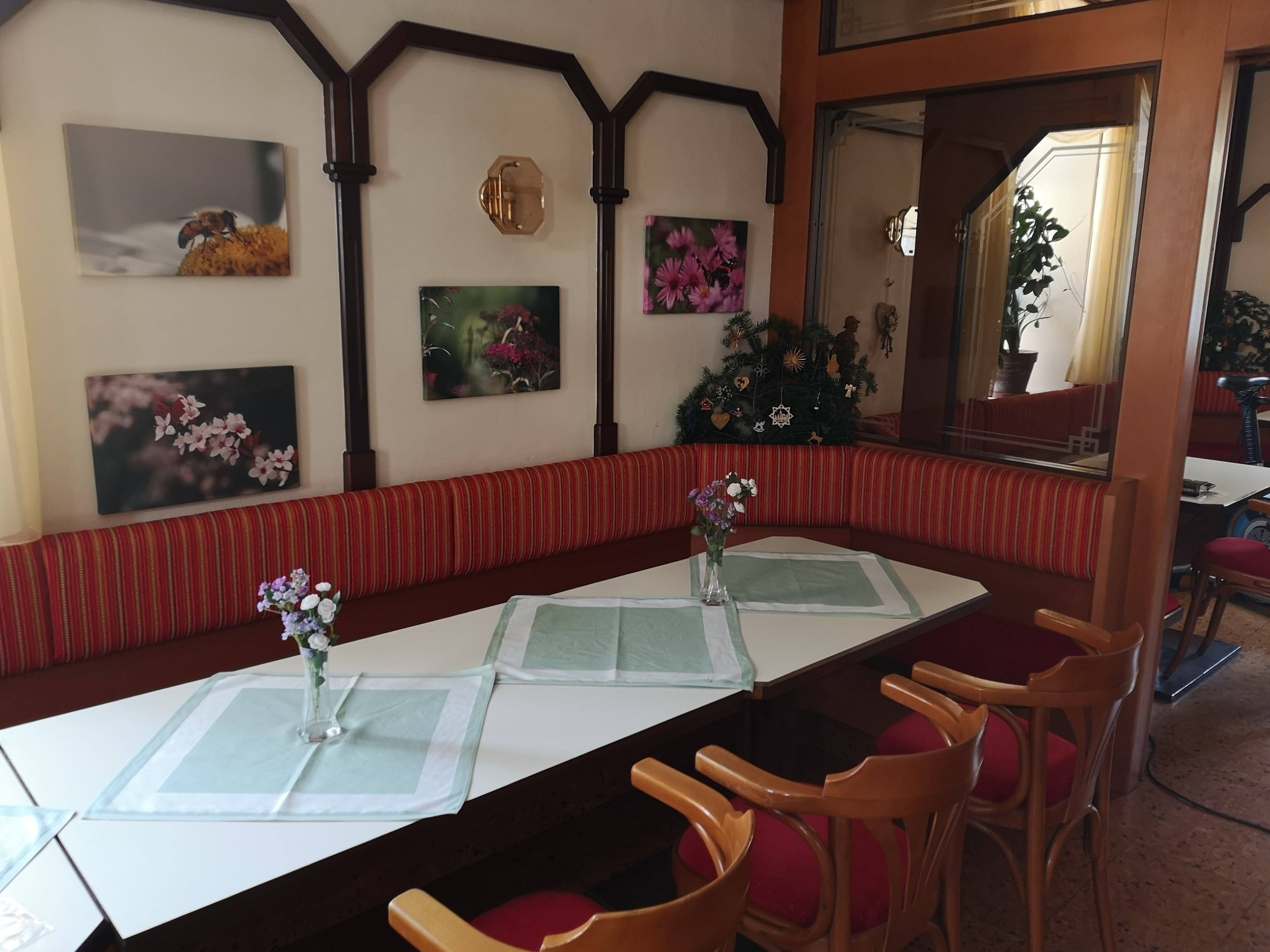 Essbereich mit Tisch, Stühlen und Blumenvasen, dekoriert mit Blumenbildern an der Wand.