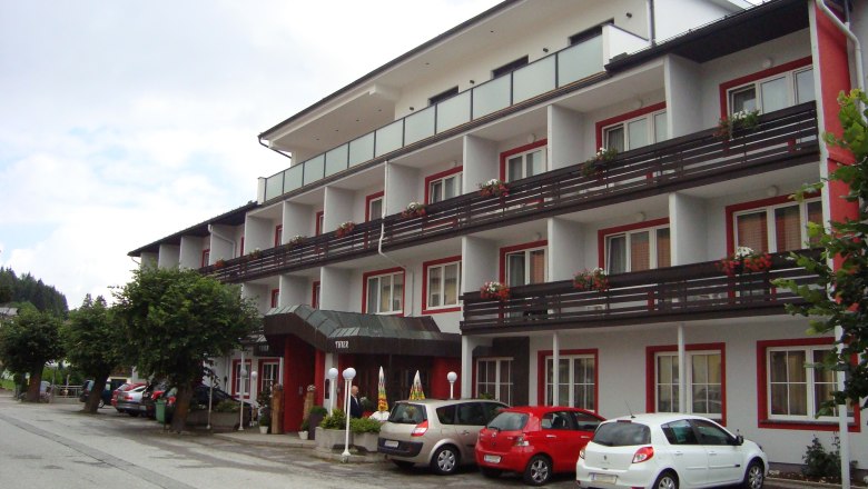 Exterior view of Hotel Thier with parked cars and balconies with flowers.