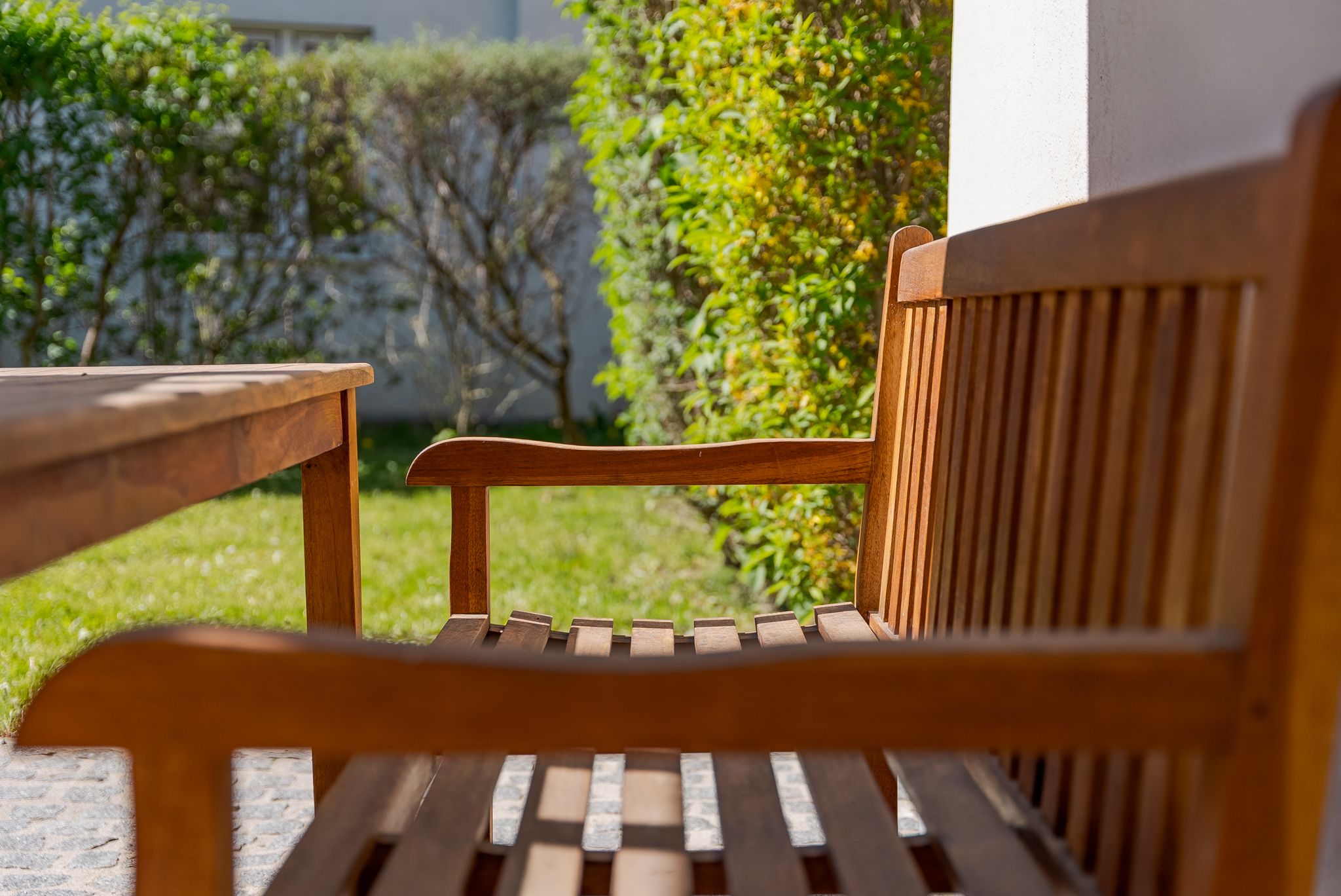 Holzbank und Tisch im Garten mit grünem Hintergrund.