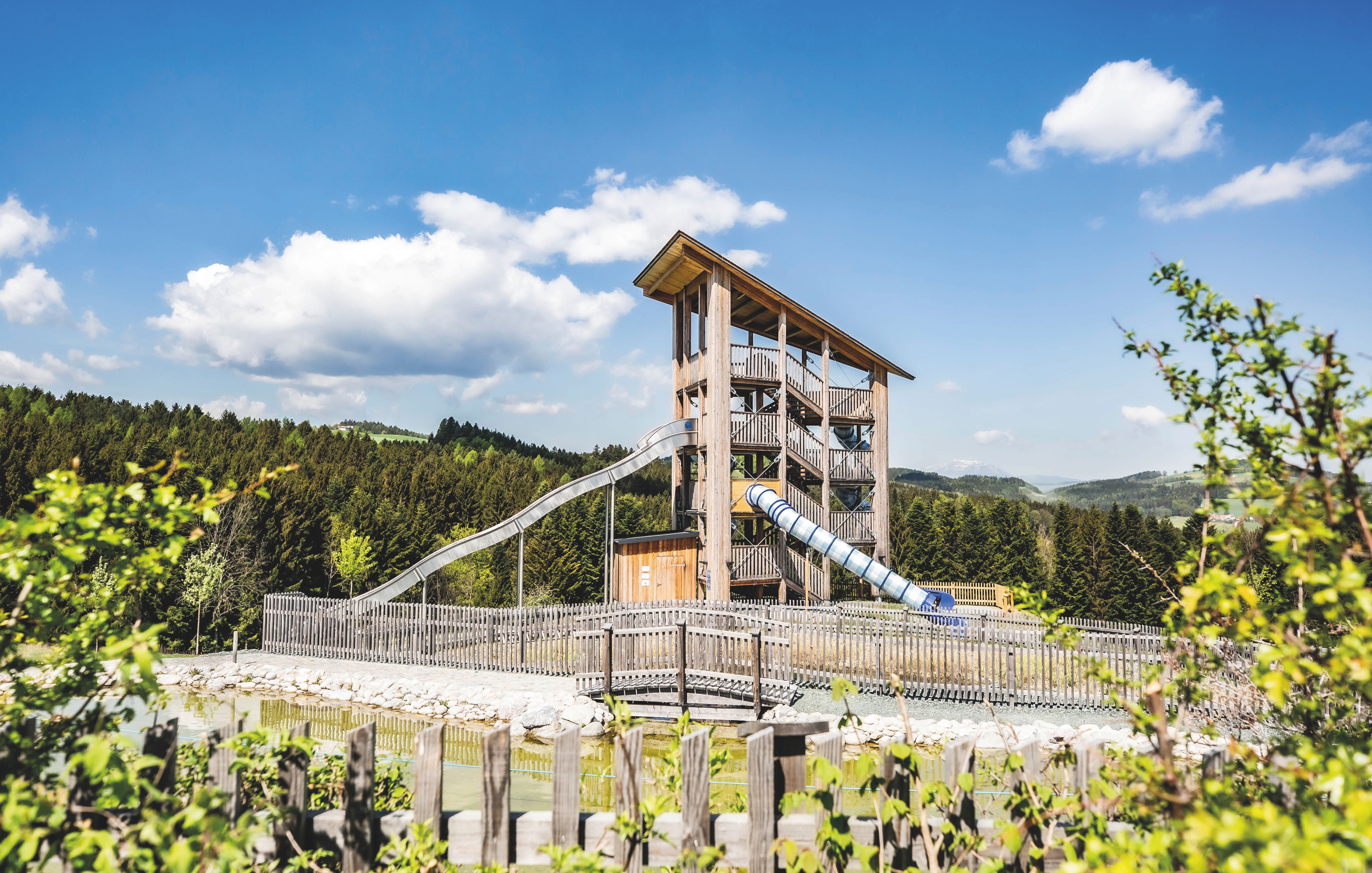 Gebäude der Eis-Greissler Welt mit Bäumen und Besuchern und Blick auf den Erlebnispark.