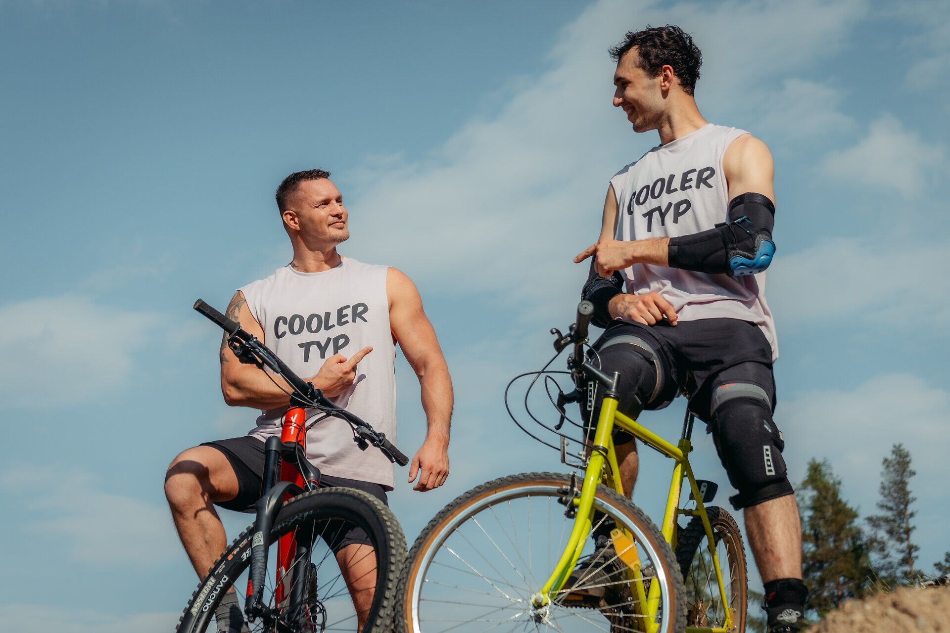 Zwei begeisterte Mountainbiker genießen die frische Bergluft und die atemberaubende Aussicht auf den Wexl Trails. Ihre sportliche Kleidung und die strahlenden Gesichter spiegeln die Freude und den Adrenalinkick wider, den die Natur und die Herausforderung des Radfahrens bieten.