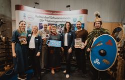 Sieben Personen mit dem Schild Wiener Alpen in Niederösterreich vor dem Stand Keltendorf Schwarzenbach