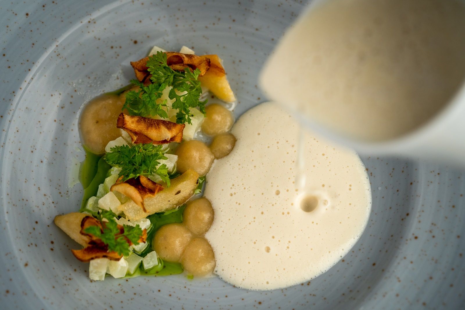 Ein elegantes Gericht mit Schaum und Gemüse auf einem Teller, übergossen mit einer hellen Sauce.