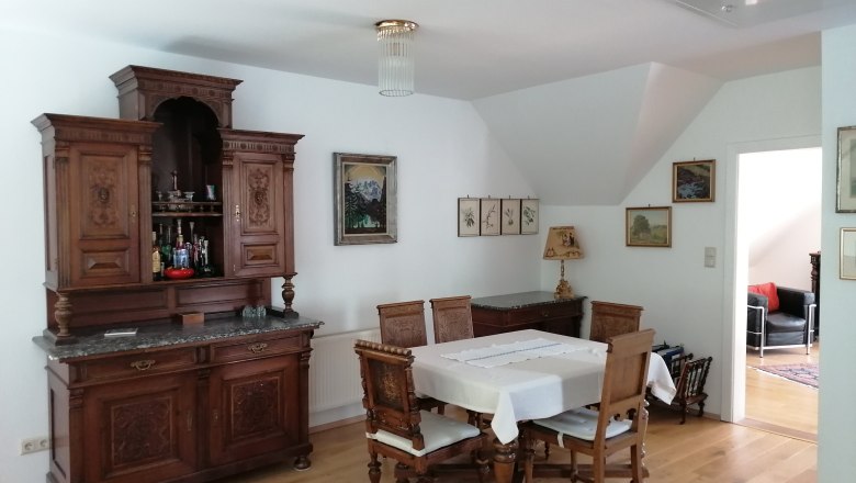 Essbereich mit antikem Holzm&ouml;bel und Esstisch mit St&uuml;hlen.