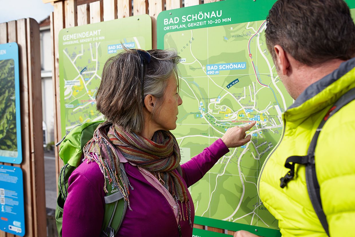 Zwei Personen betrachten eine Wanderkarte von Bad Schönau.