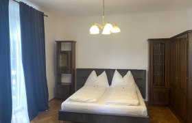 Schlafzimmer mit Doppelbett, dunklen Vorhängen und Holzschränken.