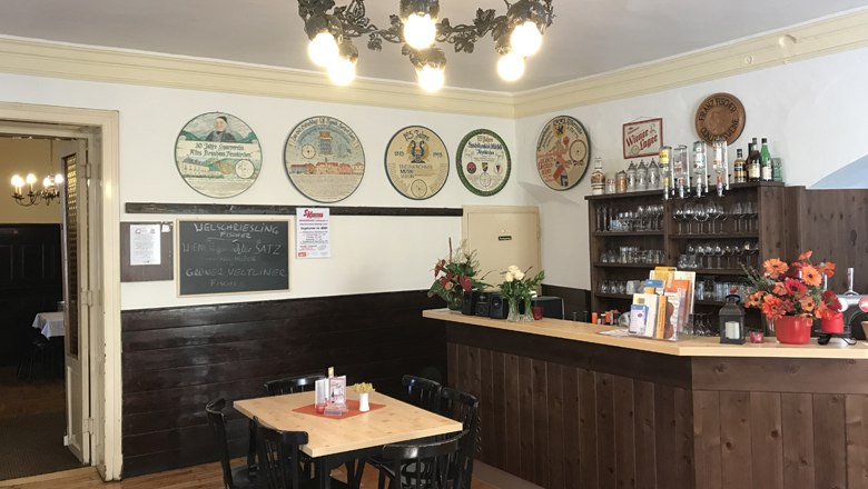 Interior view of a traditional brewery with wooden counter, tables and decorative beer mats on the wall.