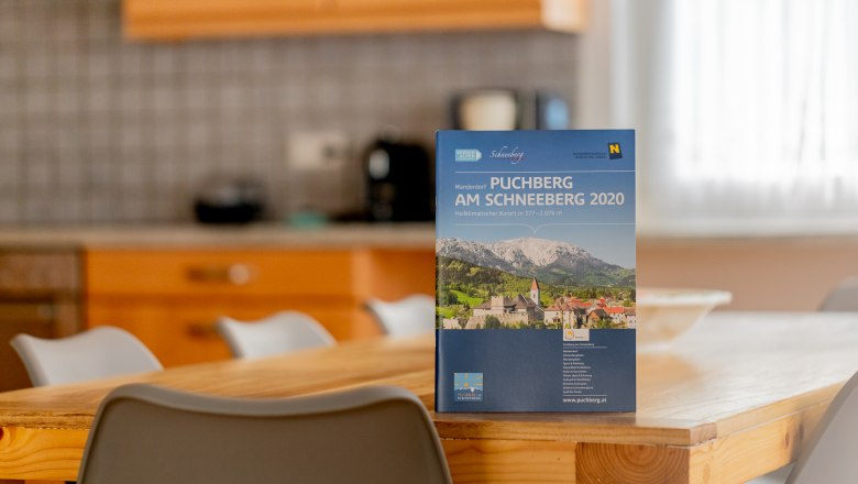 Ein Prospekt von Puchberg am Schneeberg steht auf einem Holztisch in einer Küche.