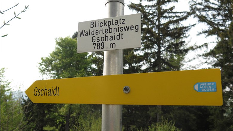 Wegweiser zum Blickplatz Walderlebnisweg Gschaidt, 789 m, mit gelbem Schild und Wiener Alpen-Bogen Logo.