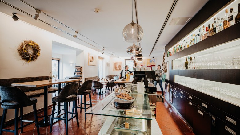 Innenansicht eines modernen Restaurants mit Bar, Tischen und Stühlen.