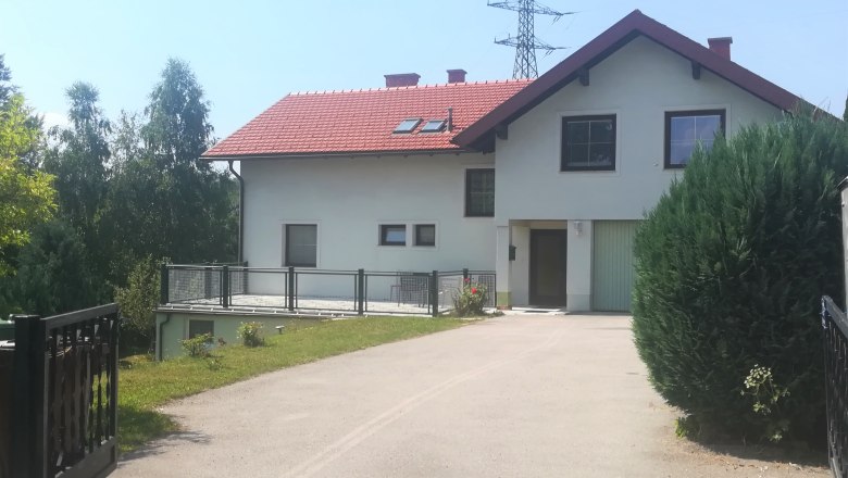 Privatzimmer Familie Holzer Hochegg, © Wiener Alpen Zweistöckiges Haus mit rotem Dach und Garage, umgeben von Bäumen und Sträuchern.