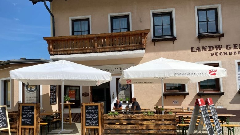 Outdoor area of a restaurant with parasols and blackboards with food offers.