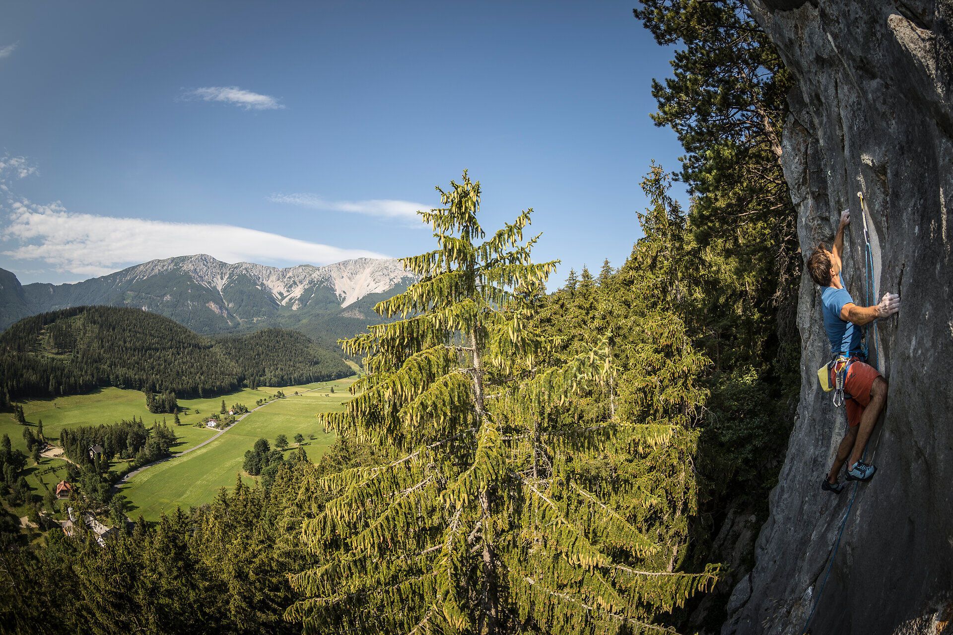 Ein Kletterer meistert mit Geschick die steilen Felsen, umgeben von der atemberaubenden Kulisse der Wiener Alpen. Die frische Bergluft und die majestätischen Ausblicke auf die umliegenden Täler schaffen ein unvergessliches Erlebnis für Abenteuerlustige.