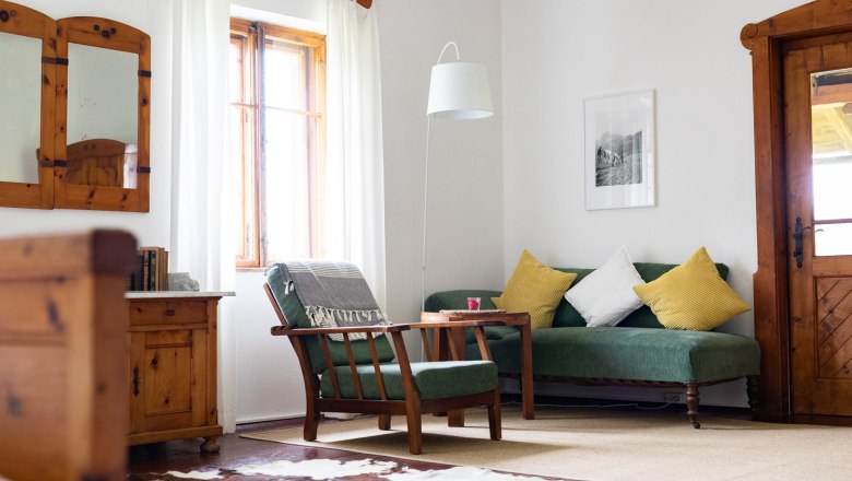 Cozy living room with wooden furniture, green sofa, yellow cushions and cowhide carpet.