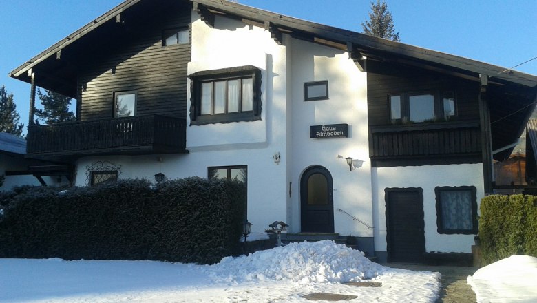 A two-storey house with wooden cladding and snow in the foreground.