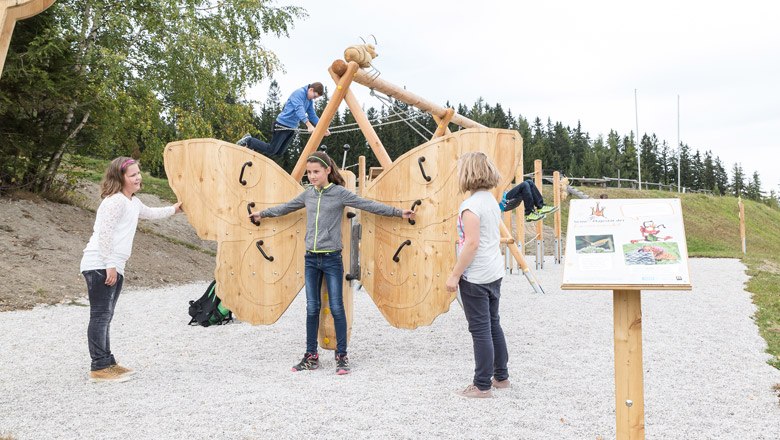 Kinder spielen auf einem gro&szlig;en Holzschmetterling auf einem Spielplatz im Freien.
