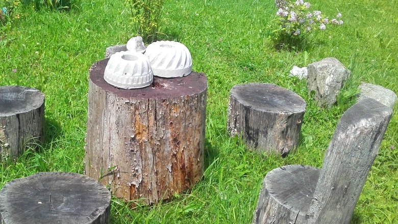 Garten mit Baumstümpfen als Sitzgelegenheiten und Tisch, dekoriert mit Betonformen.