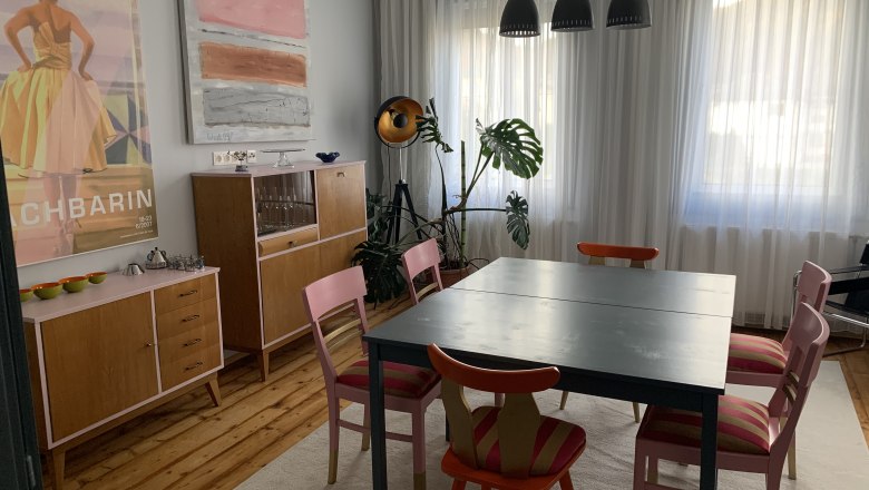 Essbereich mit Tisch, Stühlen, Kommoden und Kunstwerken an der Wand.