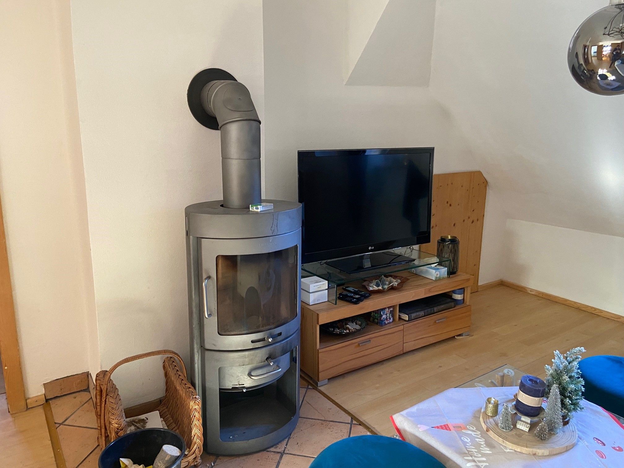 Wohnzimmer mit Kaminofen, Fernseher und dekoriertem Tisch.