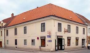Corner building with red tiled roof and several signs, including one with the inscription 'Bäckerei' (bakery).