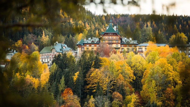 Südbahnhotel Semmering im Herbst, umgeben von buntem Laubwald.