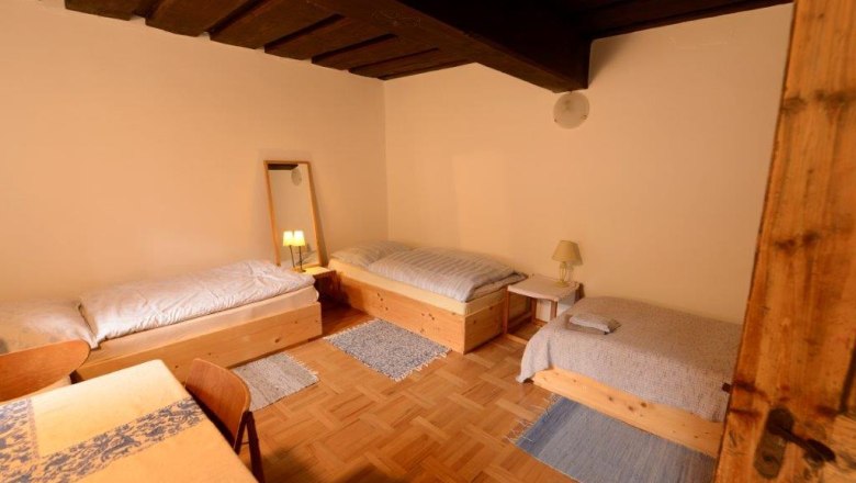 Dreibettzimmer mit Holzmöbeln und Parkettboden.